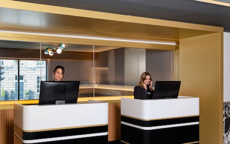 Two reception desks with computers, a modern interior, and a view of the outside.