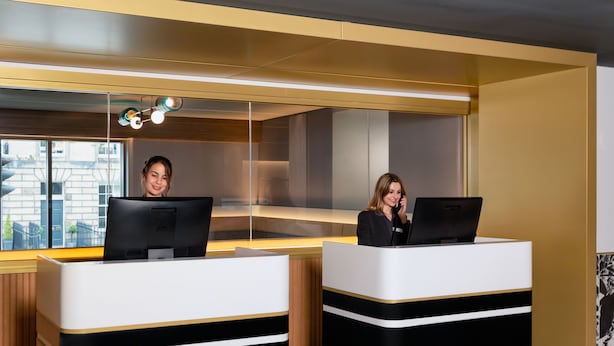 Two reception desks with computers, a modern interior, and a view of the outside.
