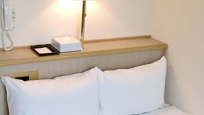 Una habitación de hotel con cama, mesita de noche, lámpara y teléfono.