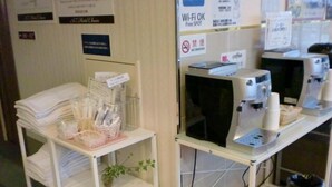 Una recepción de hotel con una pila de toallas blancas, una planta y una máquina de café.