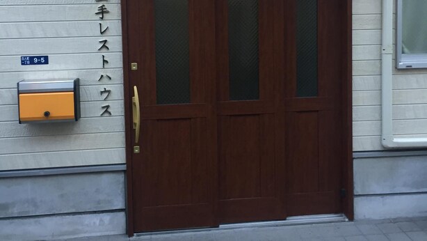 A wooden double door with a glass panel, a mailbox, and a sign with Japanese characters. - Yamate Rest House - Hostel, Caters to Men (Tokyo)