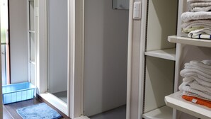 A hallway with a sliding door leading to a room, a blue plastic basket, and a pink rug on the floor. - Yamate Rest House - Hostel, Caters to Men (Tokyo)