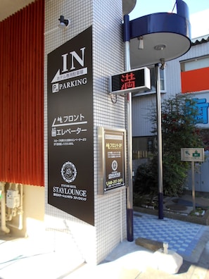 A hotel entrance with a sign indicating 'IN PARKING' and a digital display.
