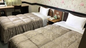 Two beds with floral-patterned bedding, a desk with a chair, a nightstand with a phone and a clock, and floral wallpaper. - Nishikawaguchi Station Hotel Stay Lounge (Kawaguchi)