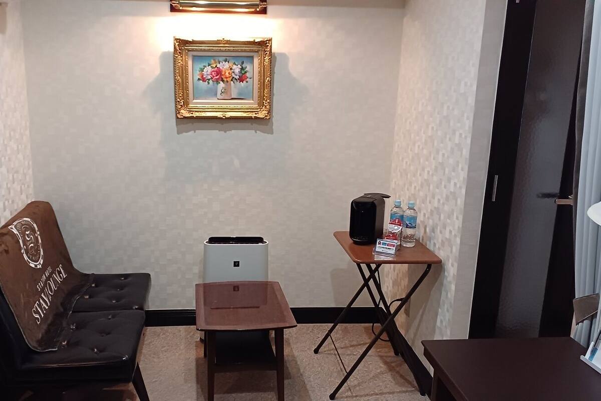 Una habitación con sofá, una mesita con un altavoz y botellas de agua, un cuadro en la pared y un purificador de aire compacto.