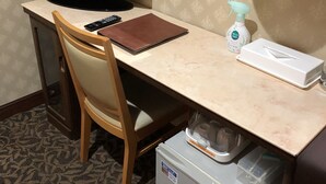 A hotel room with a desk, a television, a lamp, a spray bottle, a box, and a mini-fridge. - Nishikawaguchi Station Hotel Stay Lounge (Kawaguchi)