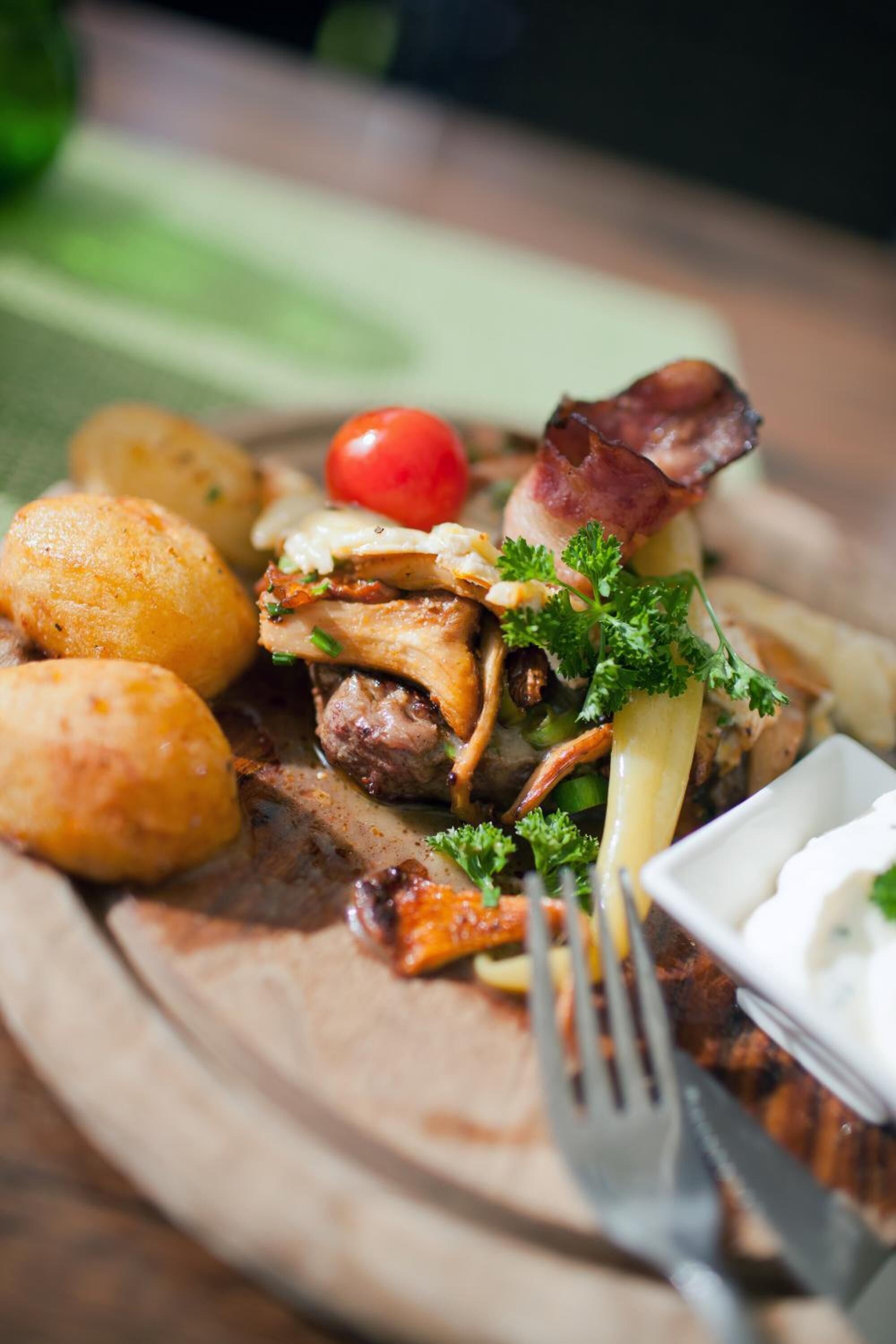 A plate of food with meat, potatoes, and a cherry tomato.