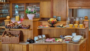 Ein reichhaltiges Buffet mit verschiedenen Speisen, darunter Früchte, Käse und Fleisch, präsentiert auf Holztischen und Regalen.