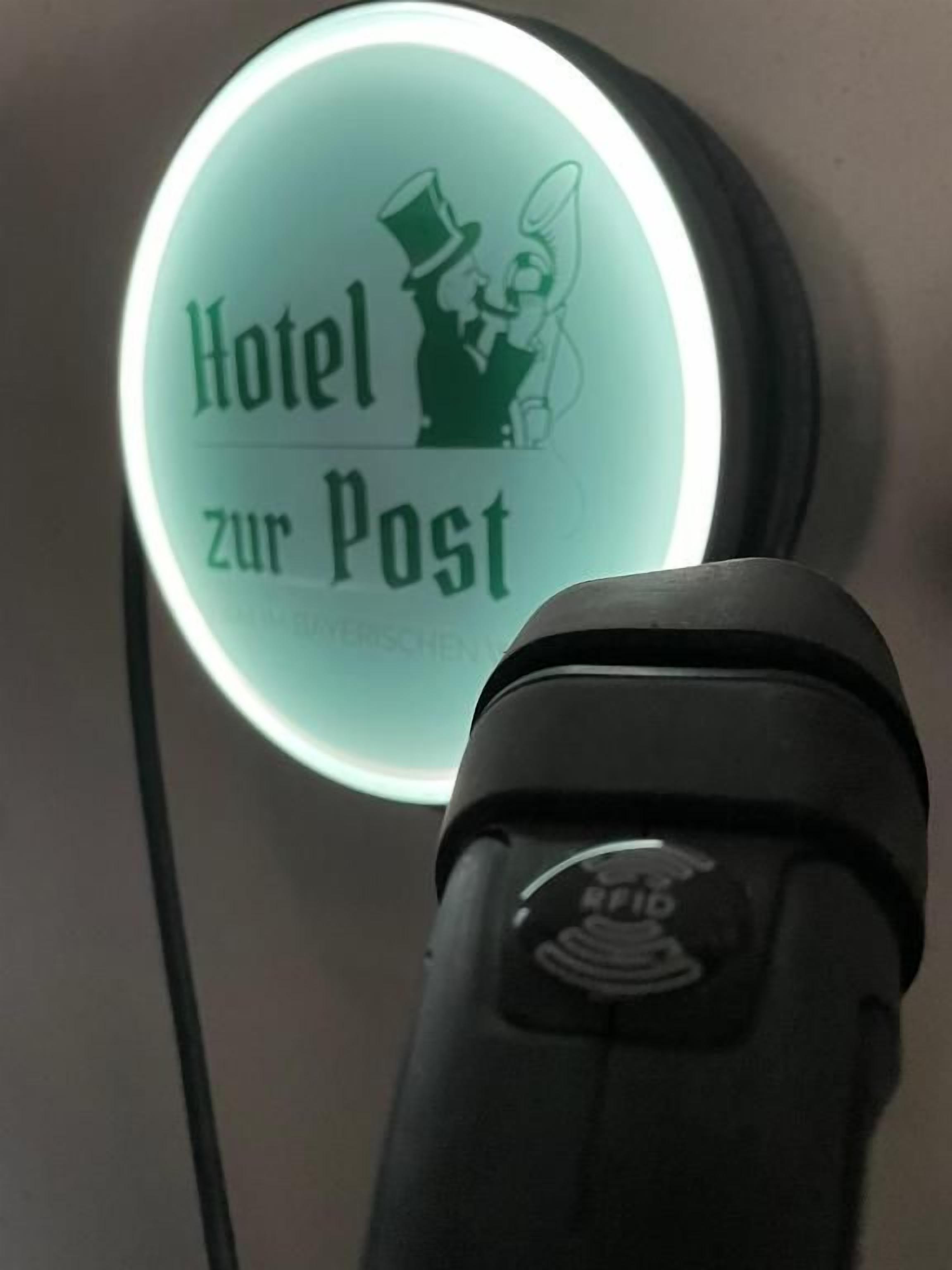 Een rond bord met de tekst 'Hotel zur Post' en een silhouet van een persoon.