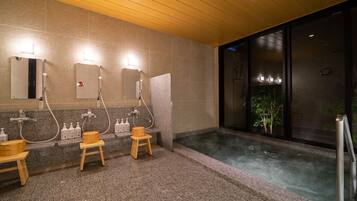 A modern bathroom with a steam shower, granite countertops, wooden stools, and a large window.