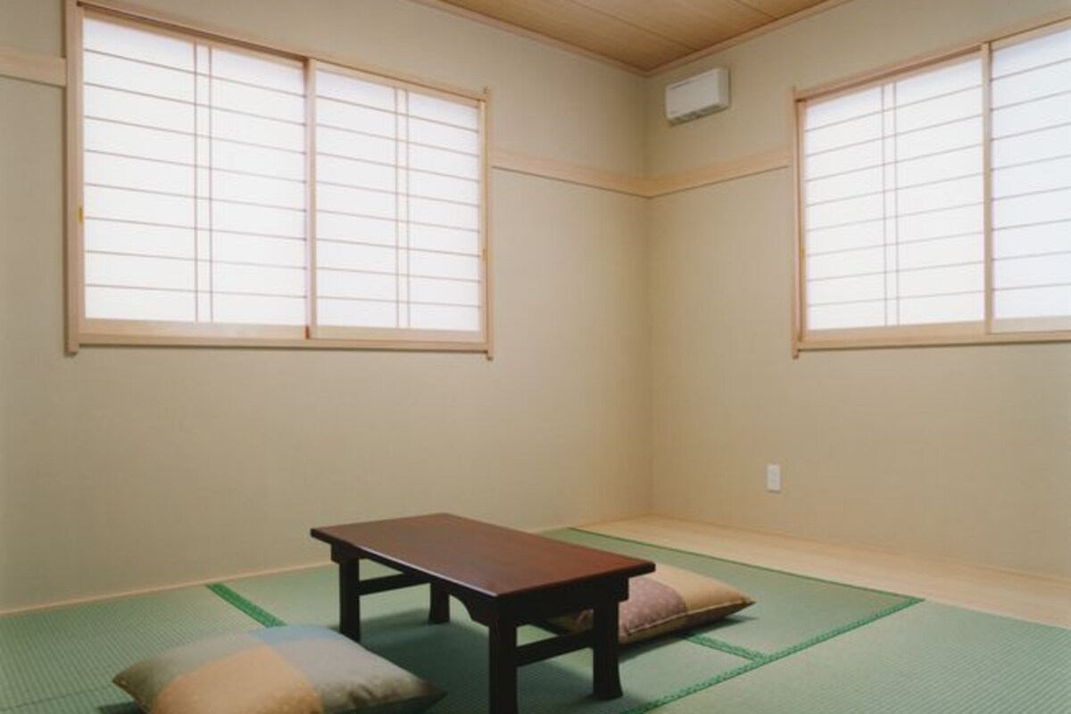A room with tatami mat flooring, a low wooden table, and two cushions.
