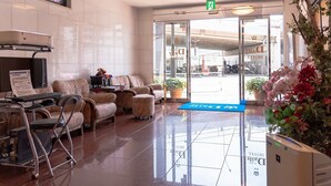 A hotel lobby with a reception desk, seating area, and a view of the hotel entrance. - Niiza Daily Hotel (Niiza)