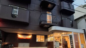 A building with a dark facade, multiple balconies, and a storefront with signage. - Business Ryokan Akashiya Annex (Akashi)