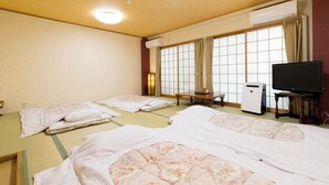 A traditional Japanese room with tatami mats, futons, a television, and an air conditioning unit. - Business Ryokan Akashiya Annex (Akashi)