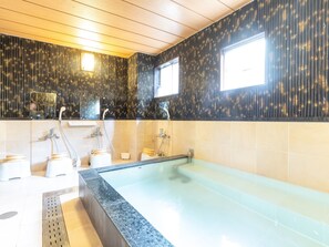 A modern bathroom with a large bathtub, a shower area, and a vanity with a mirror. - Business Ryokan Akashiya Annex (Akashi)