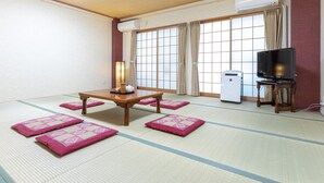 A traditional Japanese room with tatami flooring, a low table with a tea set, a television on a stand, and a sliding door with curtains. - Business Ryokan Akashiya Annex (Akashi)