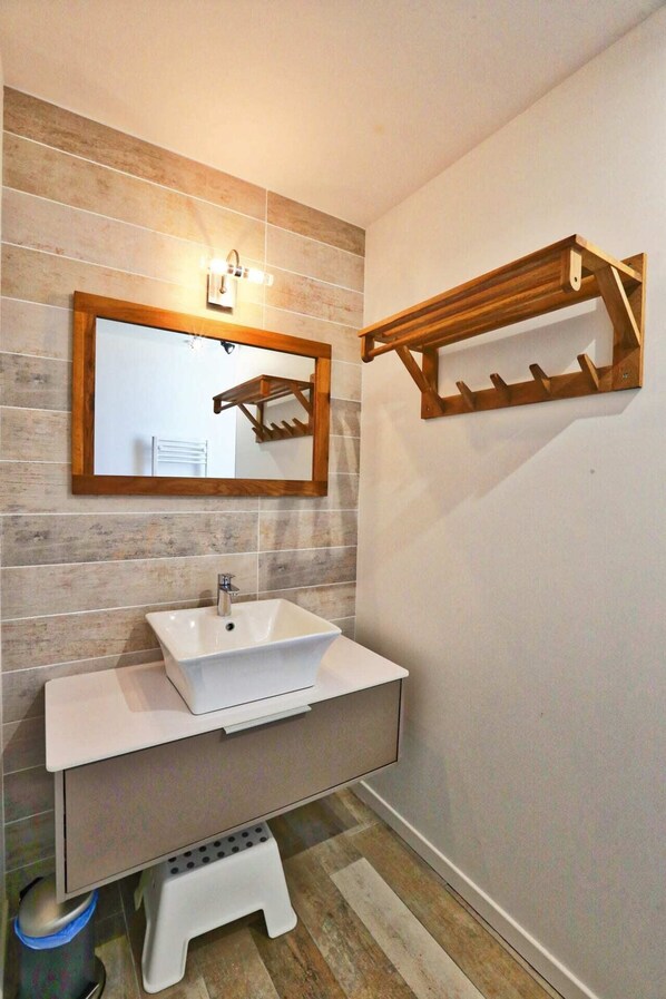 Une salle de bain avec un lavabo blanc, un miroir encadré en bois et un porte-serviettes en bois.