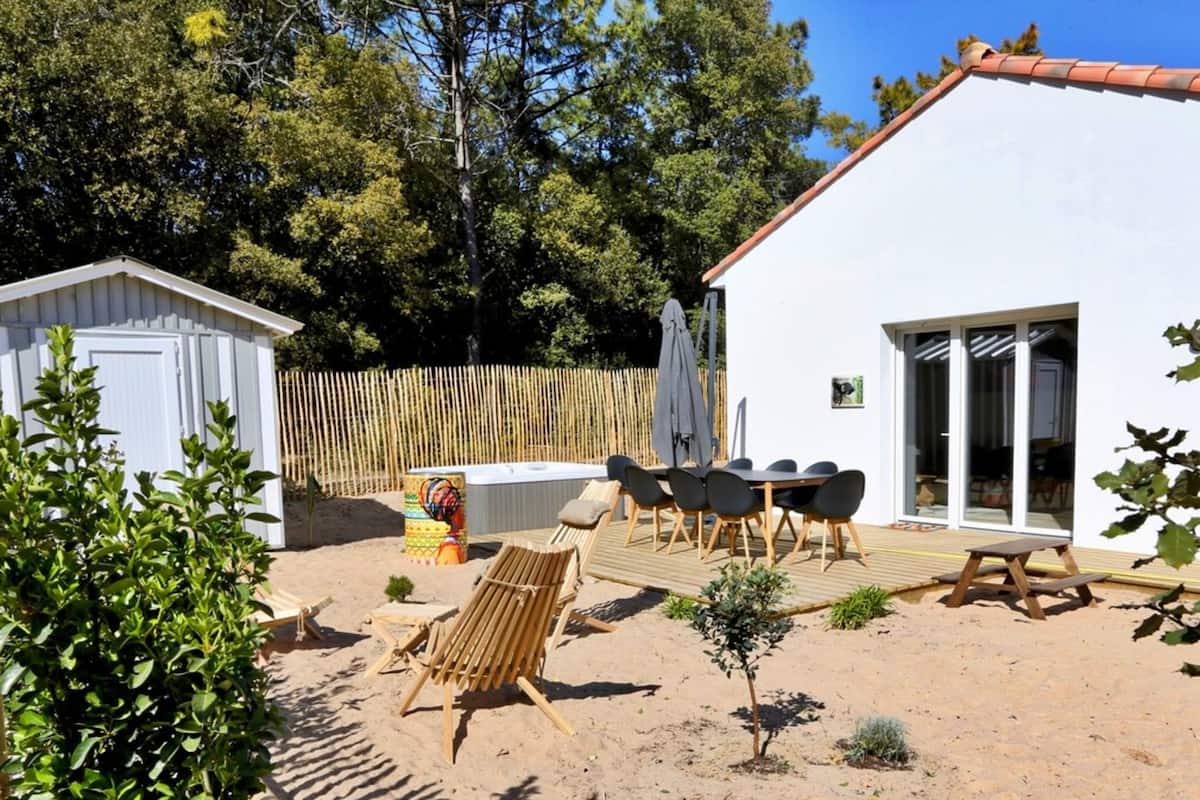 A white building with a wooden deck, outdoor seating, and a fenced area.