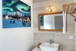 Baño con un espejo grande, un lavamanos y un perchero para toallas.