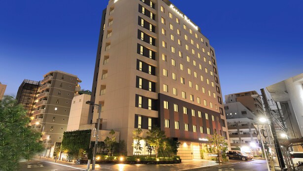 Un hotel de varios pisos con un diseño moderno, que destaca por una entrada imponente y múltiples balcones.
