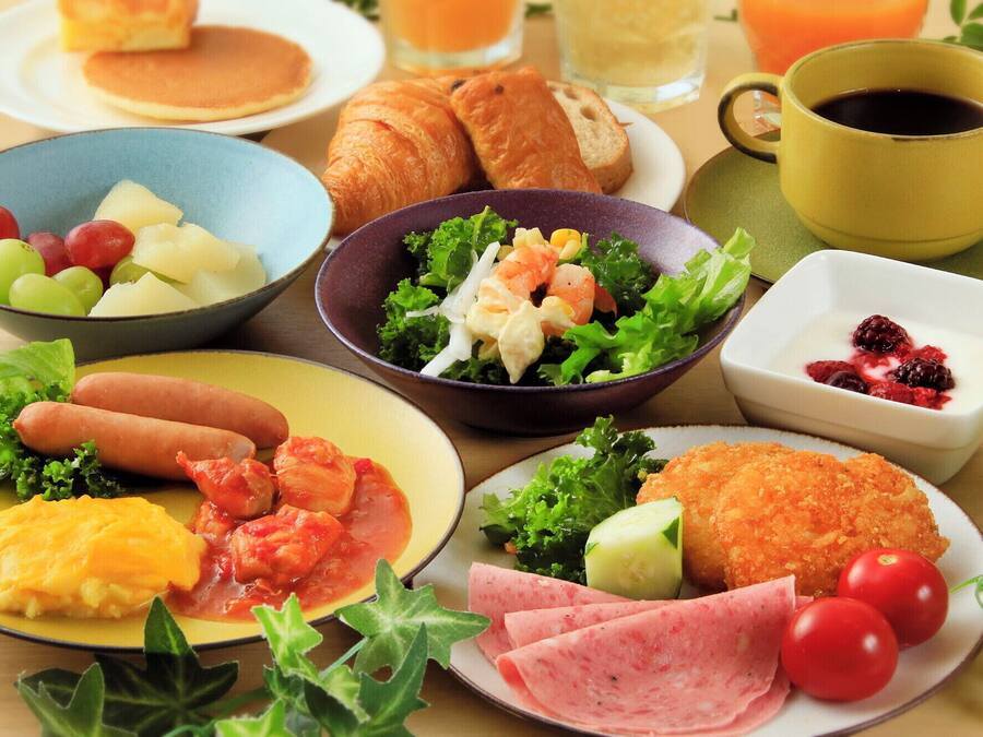 En frukostuppläggning med olika rätter, inklusive ägg, korv och en sallad.
