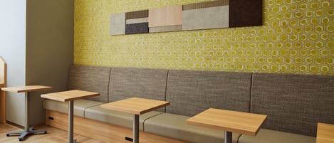 A seating area with a patterned wall, a sofa, and two tables.