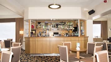 A hotel bar area with a wooden counter, various liquor bottles, and seating arrangements.