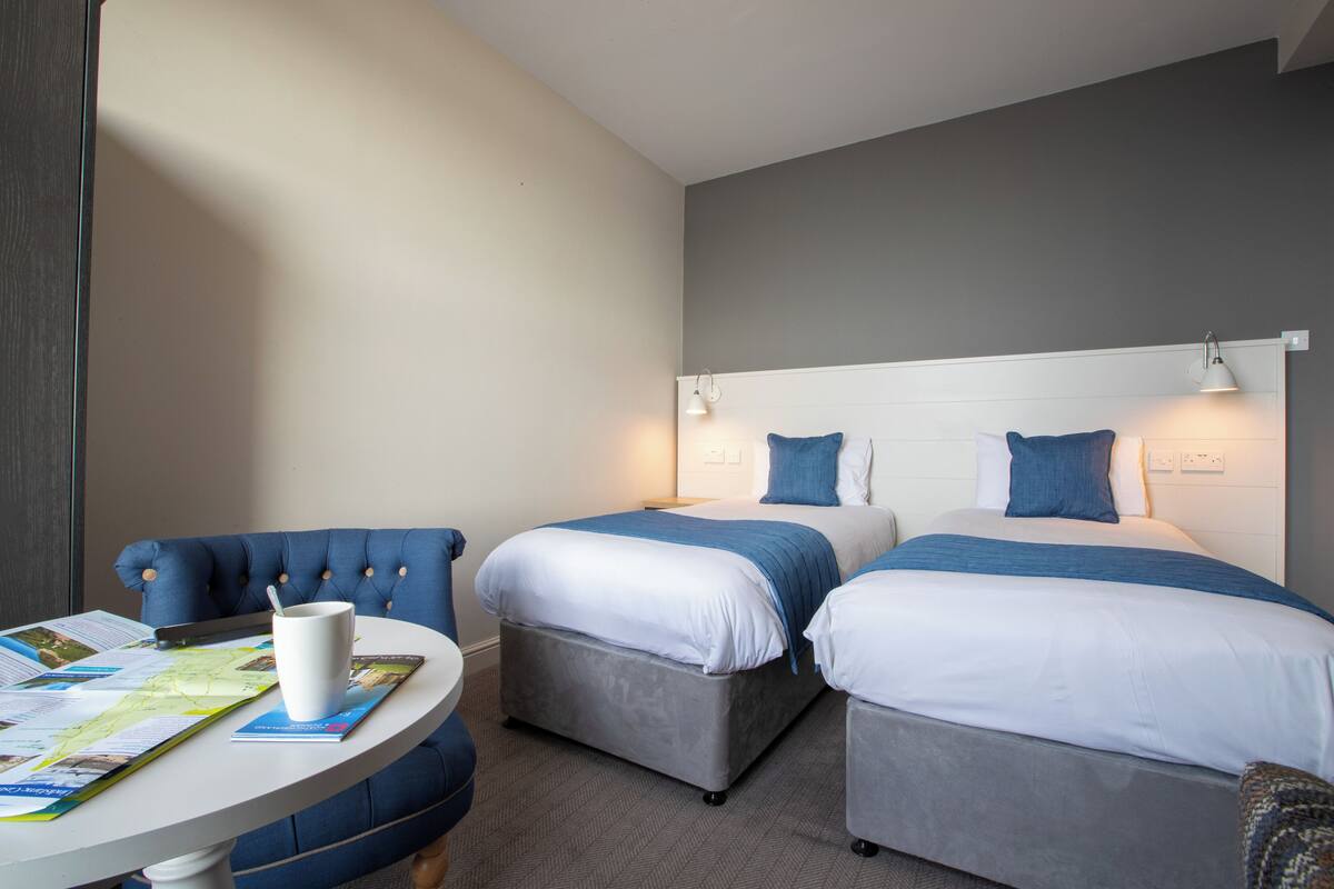 A hotel room with two beds, a dining table, and a chair.