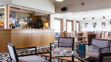 A hotel lobby with a bar area, seating arrangements, and a patterned carpet.