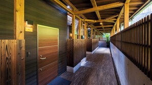 A hallway with wooden paneling and a tiled floor, leading to a door with a handle. - Yufuin ZEN - Adults Only (Yufu)