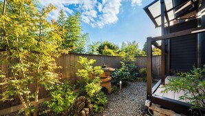 A garden with a wooden fence, a stone lantern, and a gravel path. - Yufuin ZEN - Adults Only (Yufu)