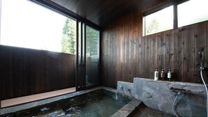 A spa area with a stone hot tub, wooden walls, and a glass door leading outside. - Yufuin ZEN - Adults Only (Yufu)