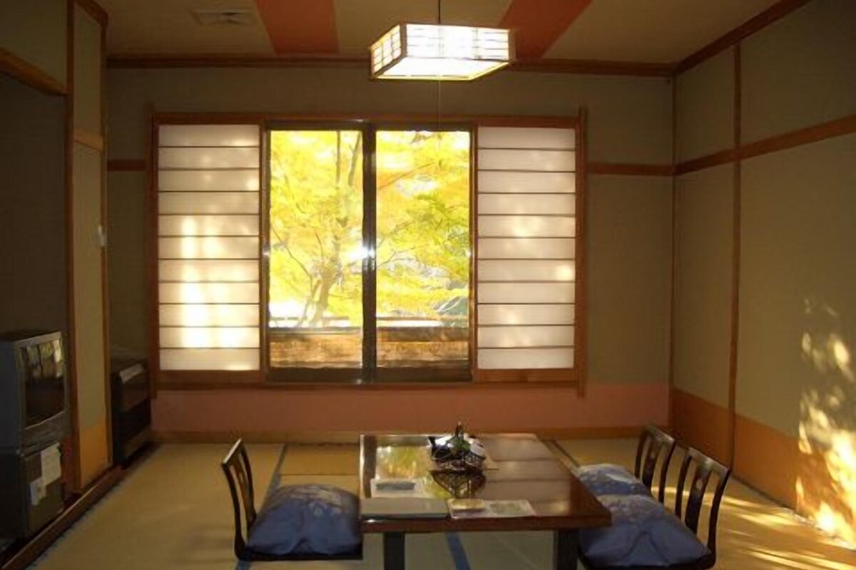 Ein traditioneller japanischer Raum mit Tatami-Böden, einem niedrigen Tisch und verschiebbaren Shoji-Türen.