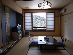 A traditional Japanese room with tatami flooring, a low table, and a television.