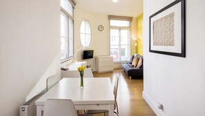 A modern living room with a white dining table, a sofa, and a TV. - Heart of Shoreditch Apartments  (London)
