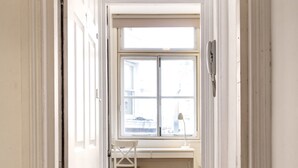 A hallway leading to a room with a large window, a desk, and a chair. - Heart of Shoreditch Apartments  (London)