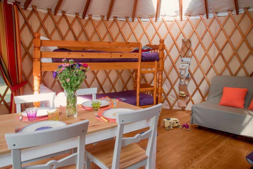 A cozy interior with a bunk bed, a dining table set for two, and a sofa.