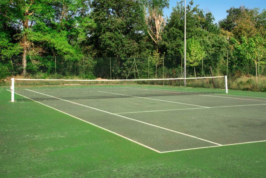 A tennis court with a net, surrounded by trees.