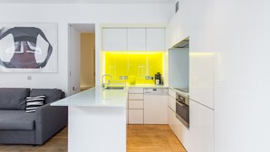 A modern kitchen with white cabinetry, a central island with a sink, and a built-in oven.