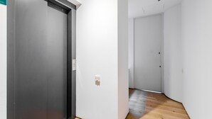A hallway with a modern elevator and a door leading to another room.