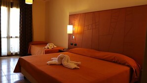 A hotel room with two beds, a nightstand, a lamp, and a window with curtains.