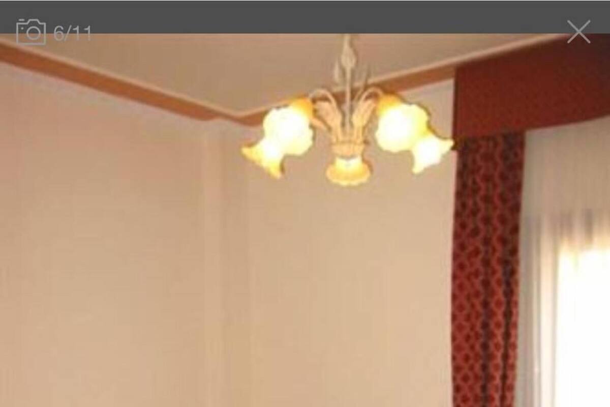 Une chambre d’hôtel avec un grand lit, une table de chevet, une lampe et une fenêtre avec des rideaux.