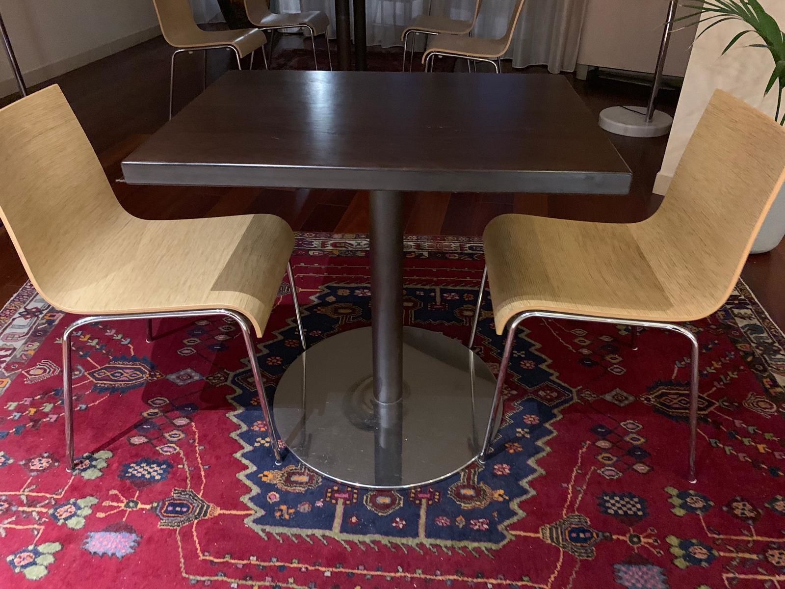 Un comedor con una mesa redonda y cuatro sillas, un tapete estampado y una planta en maceta.
