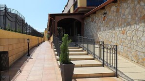 A building with a stone facade, a tiled walkway, and a potted plant.