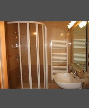 Bathroom features a curved shower enclosure, a sink with a chrome faucet, and a mirror.