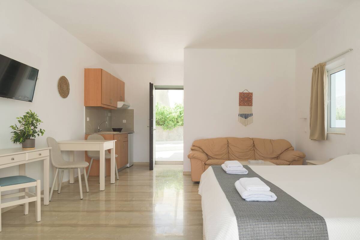 A modern hotel room with a bed, a desk, a chair, a television, and a view of the outdoors.