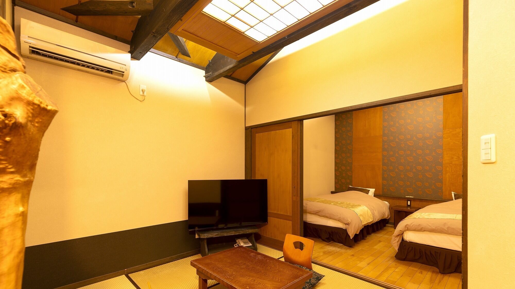 Ein Hotelzimmer mit einem Bett, einem Fernseher, einem kleinen Tisch und einem Spiegel, der das Zimmer widerspiegelt.