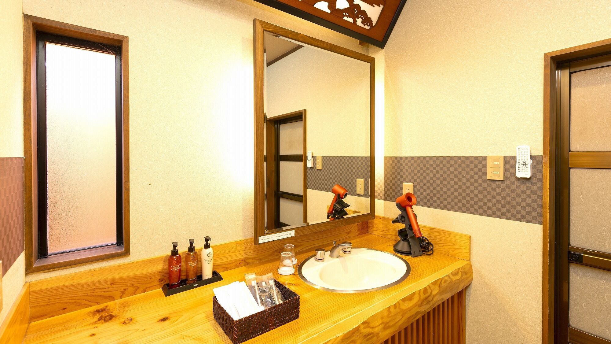 Ein Hotelbad mit einem Holzinlay, einem großen Spiegel, einem Waschbecken und Pflegeprodukten.