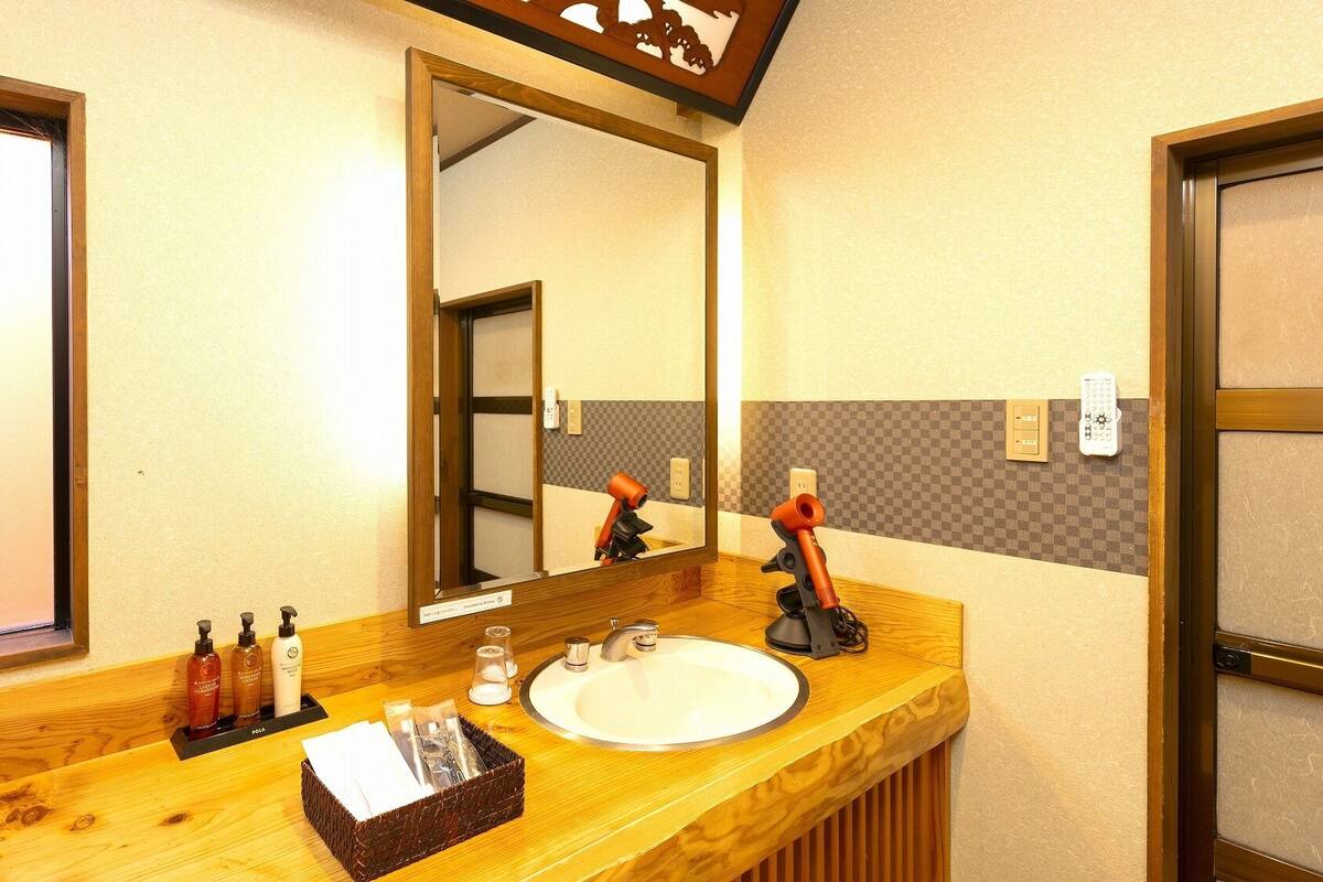 A hotel bathroom with a wooden vanity, a large mirror, a sink, and toiletries.