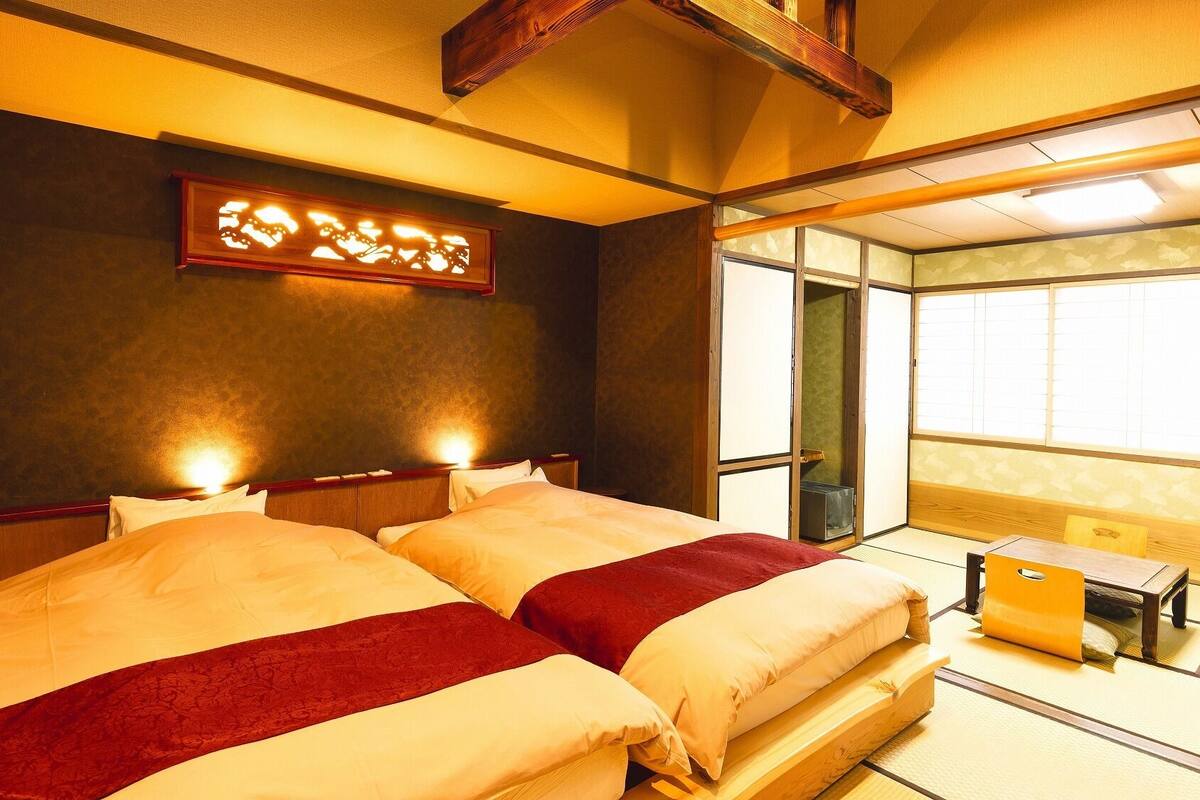 A hotel room with two beds, a wooden headboard, a wall-mounted light fixture, and a sliding door leading to a balcony.